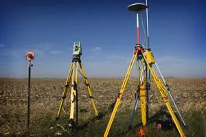 Statywy z instrumentami geodezyjnymi w polu